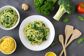 A bowl of Broccoli and Spinach Pasta with cooked broccoli florets, spinach, peas, and pasta, coated in marinara sauce and topped with grated Parmesan cheese. The dish is served in a light bowl with a fork beside it, creating a wholesome and nutritious meal for kids.
